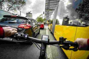 Cyclist travelling between vehicles and a bus in heavy urban traffic.