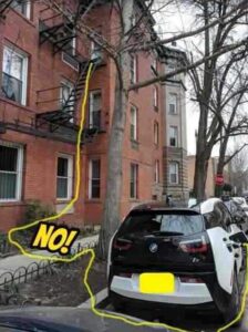 Electric BMW charging from an extension cord hanging from an apartment building onto a Toronto street.