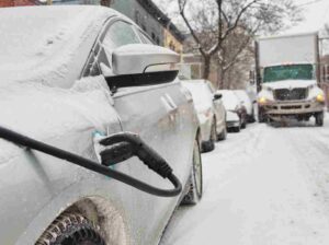 Electric vehicle charging on a snow-covered Toronto street during winter weather conditions